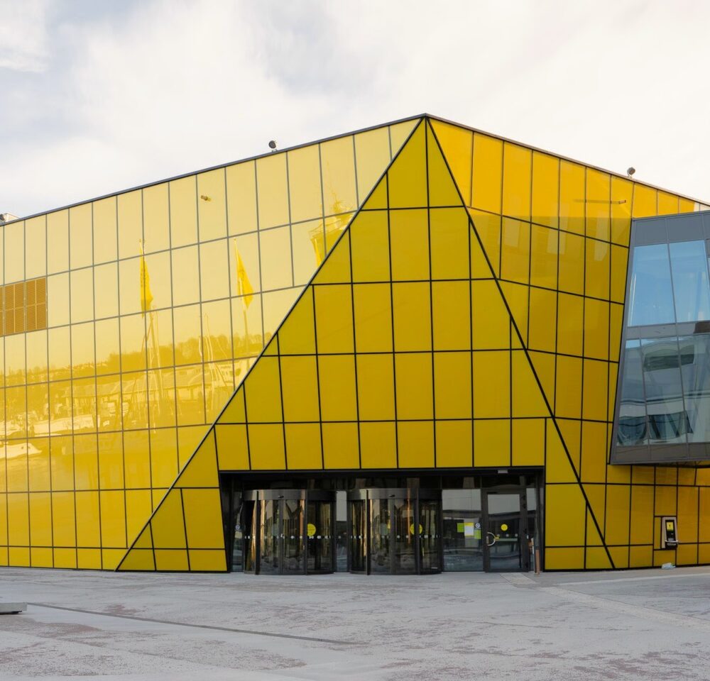 Entrance of Linnaeus University framed by a triangular pattern in the yellow glass facade